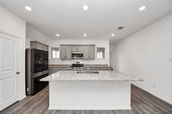 a kitchen with stainless steel appliances granite countertop a sink a stove a refrigerator a microwave and cabinets