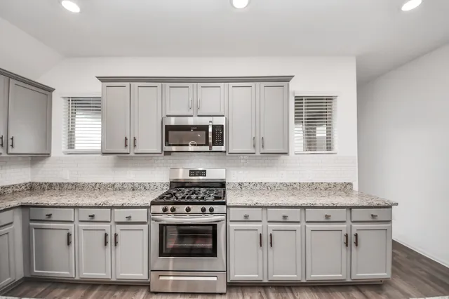 a kitchen with granite countertop white cabinets and appliances