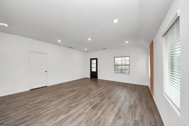 a view of an empty room with wooden floor and a window