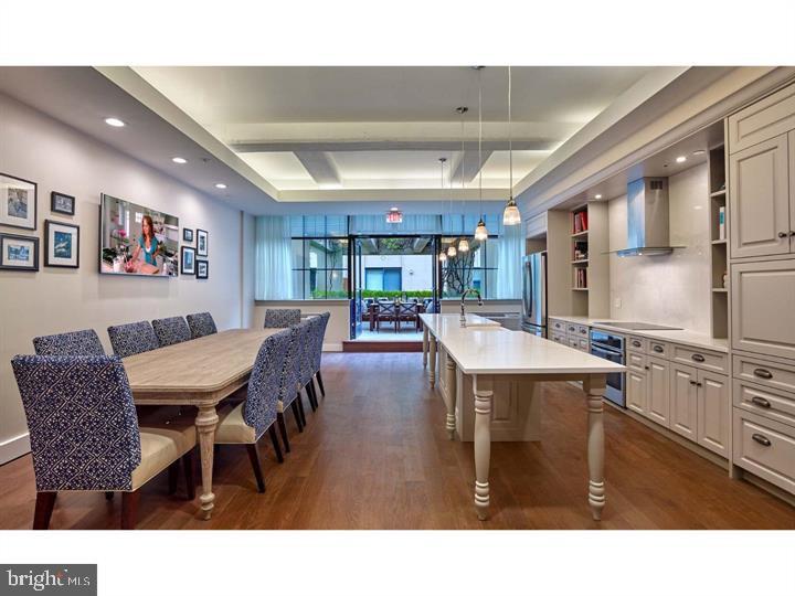 3131 Walnut Street, Unit 3B333 Philadelphia, PA 19104 - Photo 6 of 10 a open kitchen with stainless steel appliances kitchen island granite countertop a dining table chairs and a refrigerator