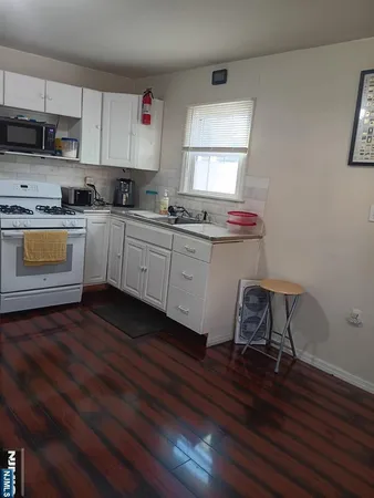 a kitchen with a sink a stove cabinets and wooden floor