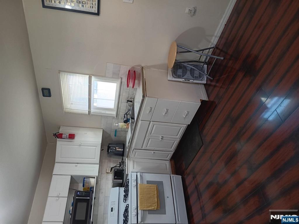 40 Poplar Street Lodi, NJ 07644 - Photo 3 of 13 a kitchen with a sink a stove cabinets and wooden floor