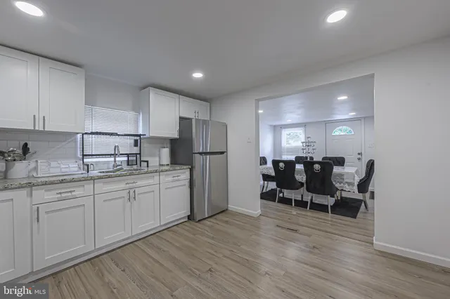 a kitchen with stainless steel appliances granite countertop a white cabinets and chairs