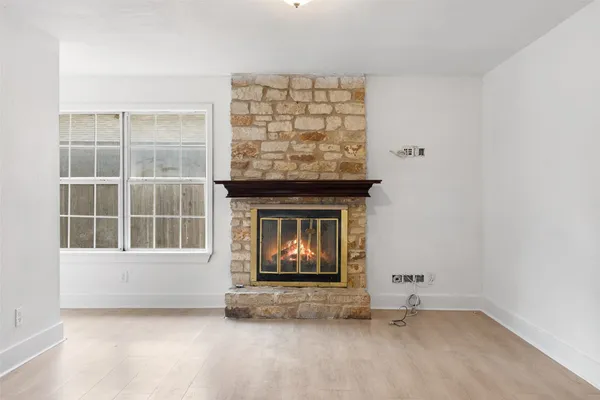 a view of an empty room with a window and fireplace