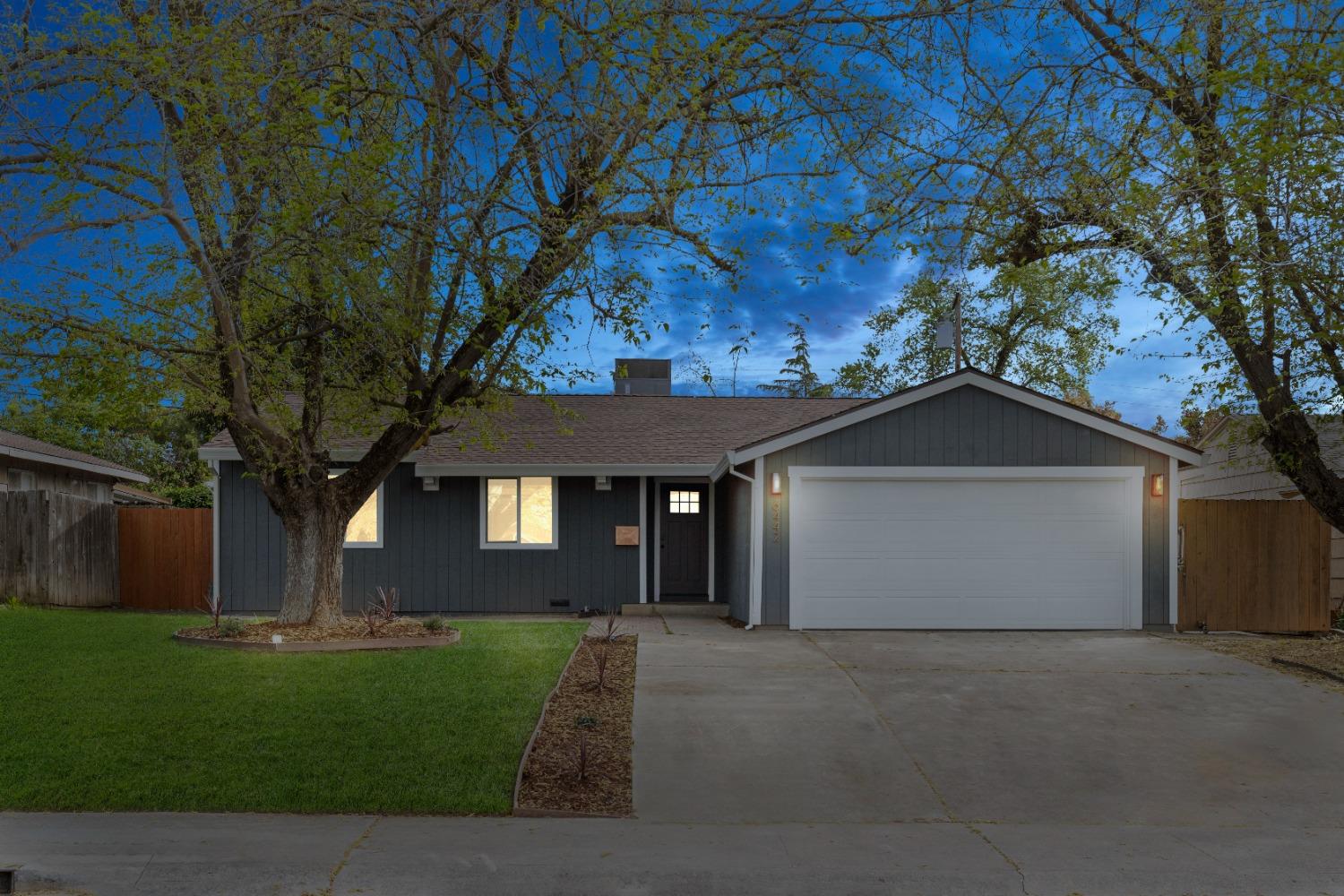 a front view of a house with a garden and trees
