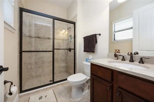 a bathroom with a granite countertop sink toilet a mirror and shower