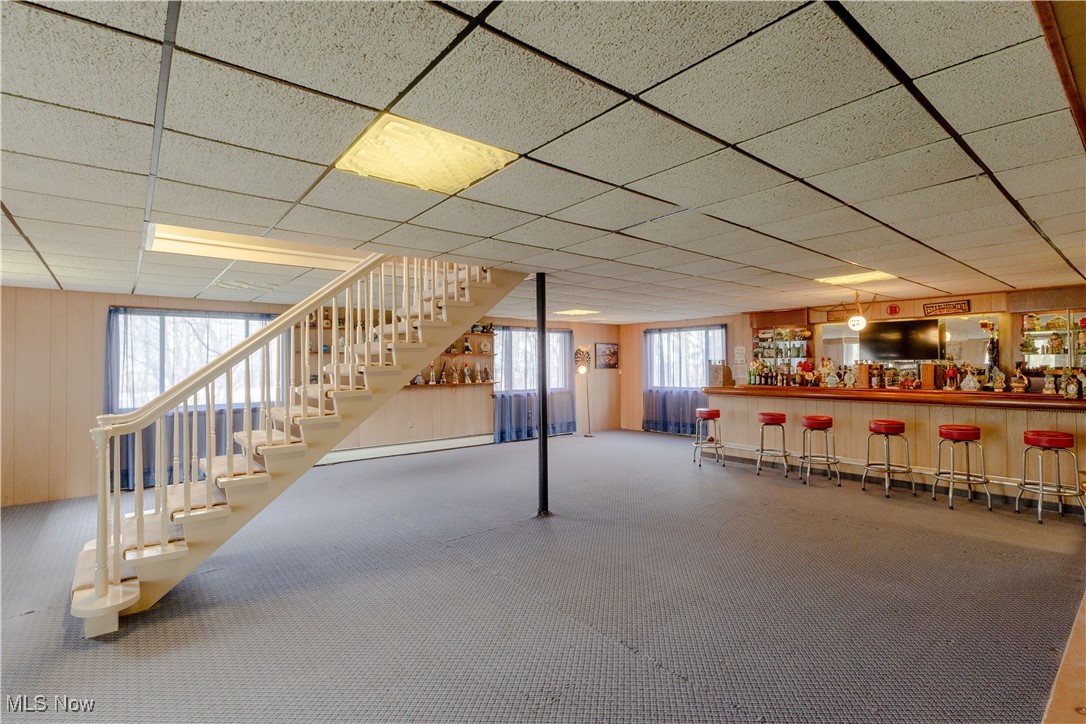 1639 South Ridge Road West Ashtabula, OH 44004 - Photo 34 of 44 Basement featuring a bar, stairway, a baseboard radiator, and carpet