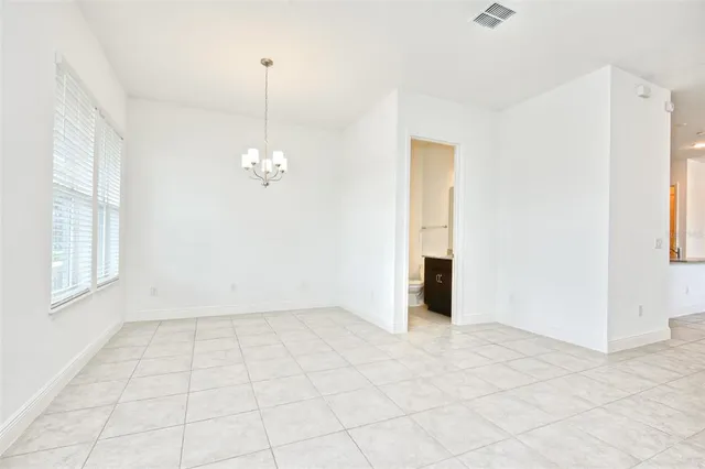 an empty room with chandelier fan and windows