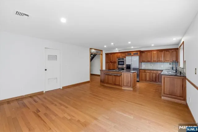 a kitchen with stainless steel appliances granite countertop a stove a sink and a refrigerator