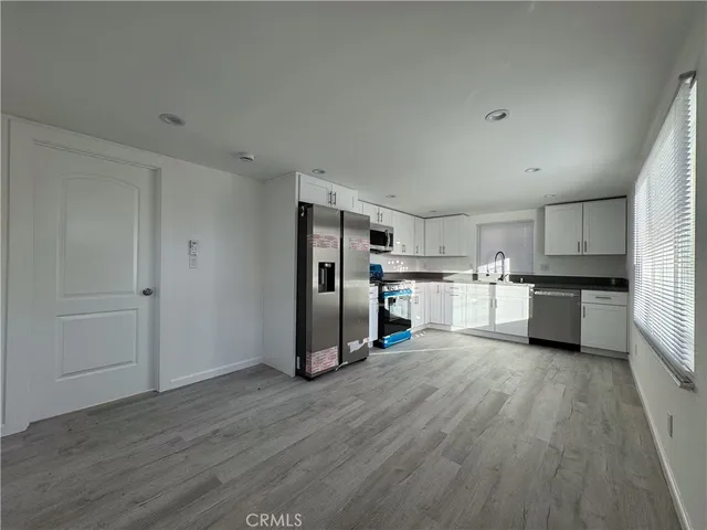 a kitchen with stainless steel appliances wooden floor and white cabinets