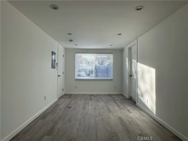 a view of an empty room with a window and wooden floor
