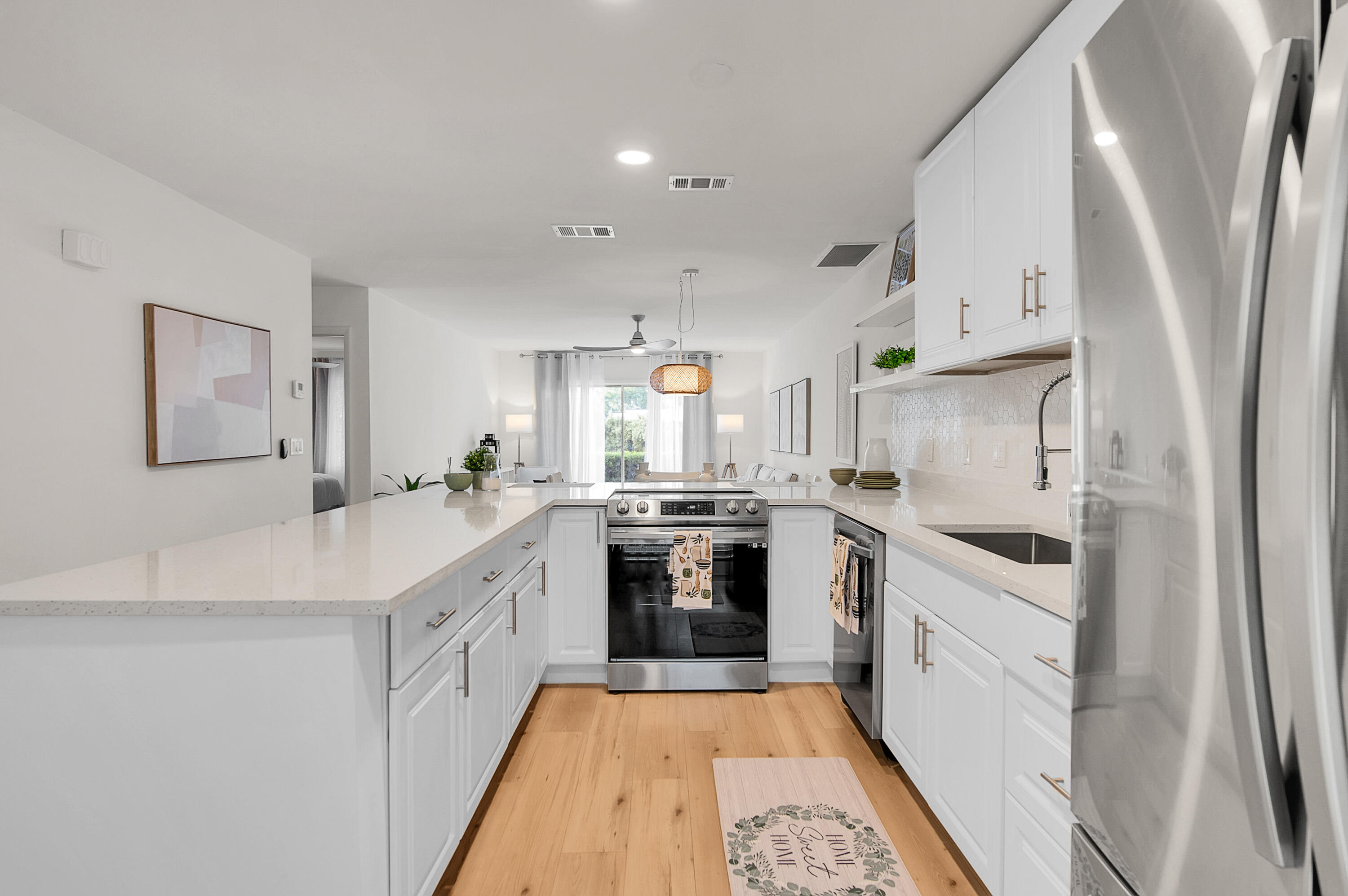 8799 Bella Vista Drive Boca Raton, FL 33433 - Photo 1 of 58 a large white kitchen with stainless steel appliances granite countertop a lot of white cabinets and wooden floor