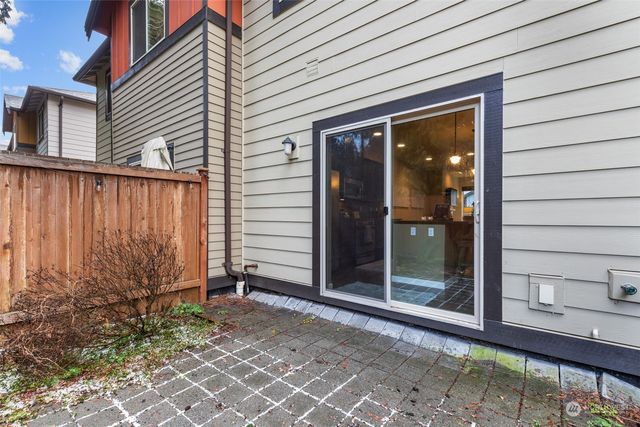 a backyard of a house with plants and trees with wooden fence