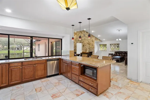 a large kitchen with stainless steel appliances granite countertop a stove and a view of living room