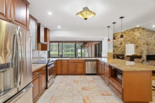 a large kitchen with stainless steel appliances granite countertop a refrigerator a sink and dishwasher