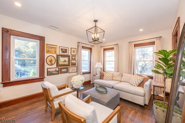 a living room with furniture a chandelier and wooden floor