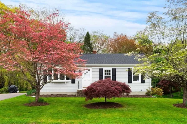a front view of a house with a garden and trees