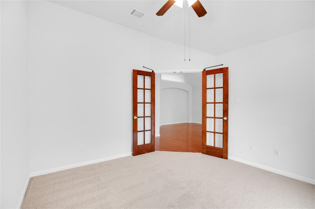 281 Hutton Kyle, TX 78640 - Photo 21 of 37 French doors open into a bright room, featuring plush carpet and a classic ceiling fan.
