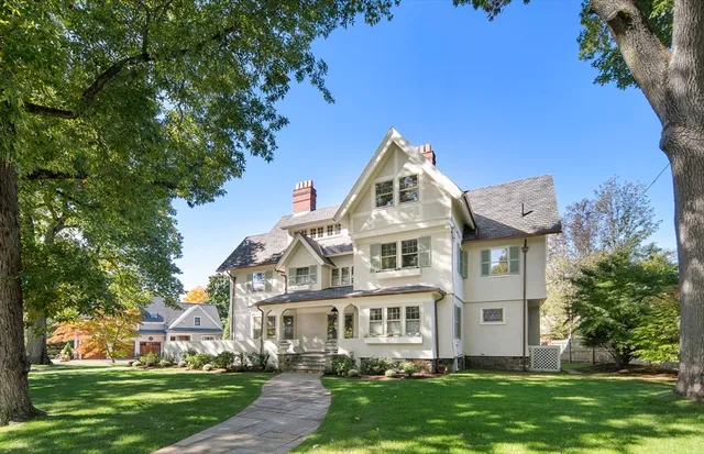 a view of a white house next to a yard with big trees
