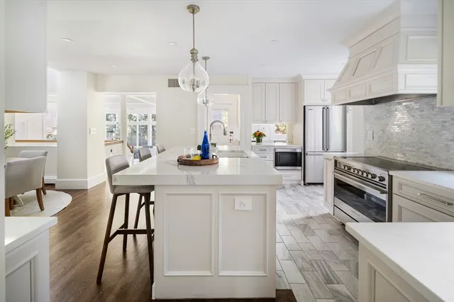 a kitchen with stainless steel appliances kitchen island granite countertop a table chairs in it and white cabinets