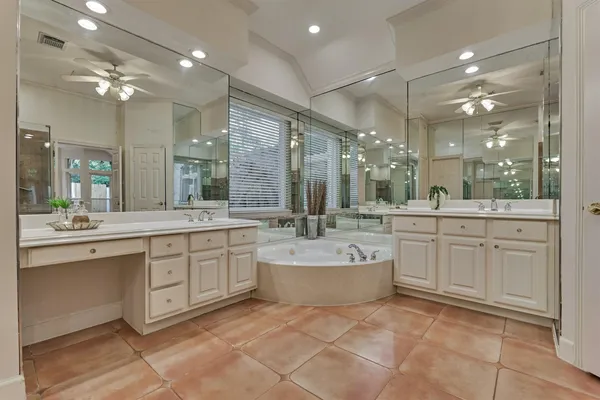 a bathroom with a sink vanity tub shower and a mirror
