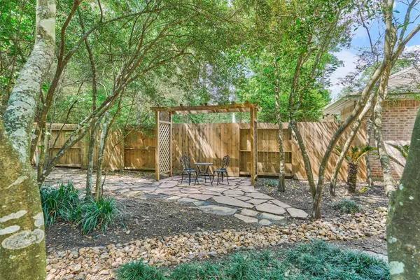 a backyard of a house with large trees and wooden fence