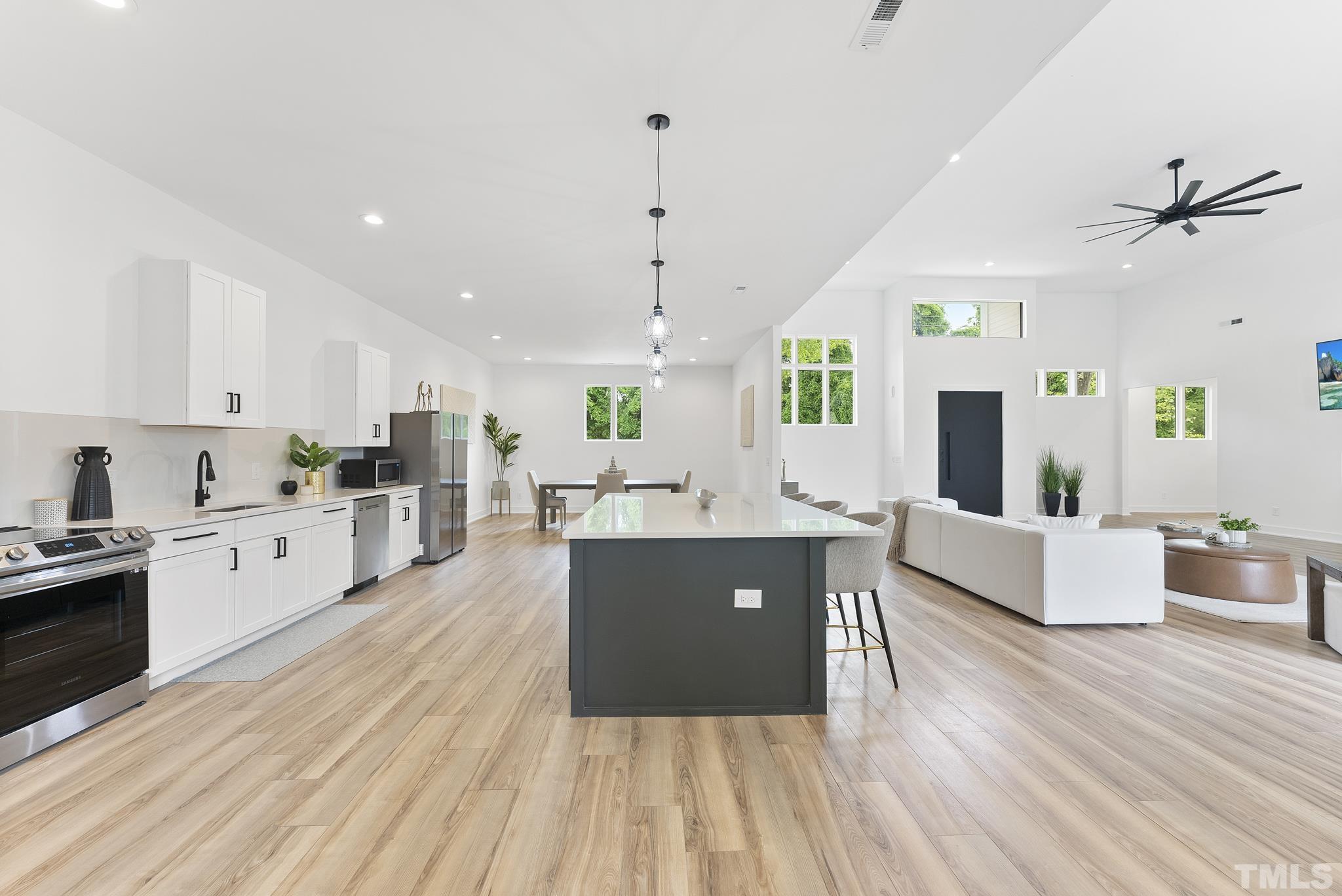 1920 Cook Road Durham, NC 27713 - Photo 15 of 43 a large kitchen with kitchen island a white counter space a sink a window and stainless steel appliances