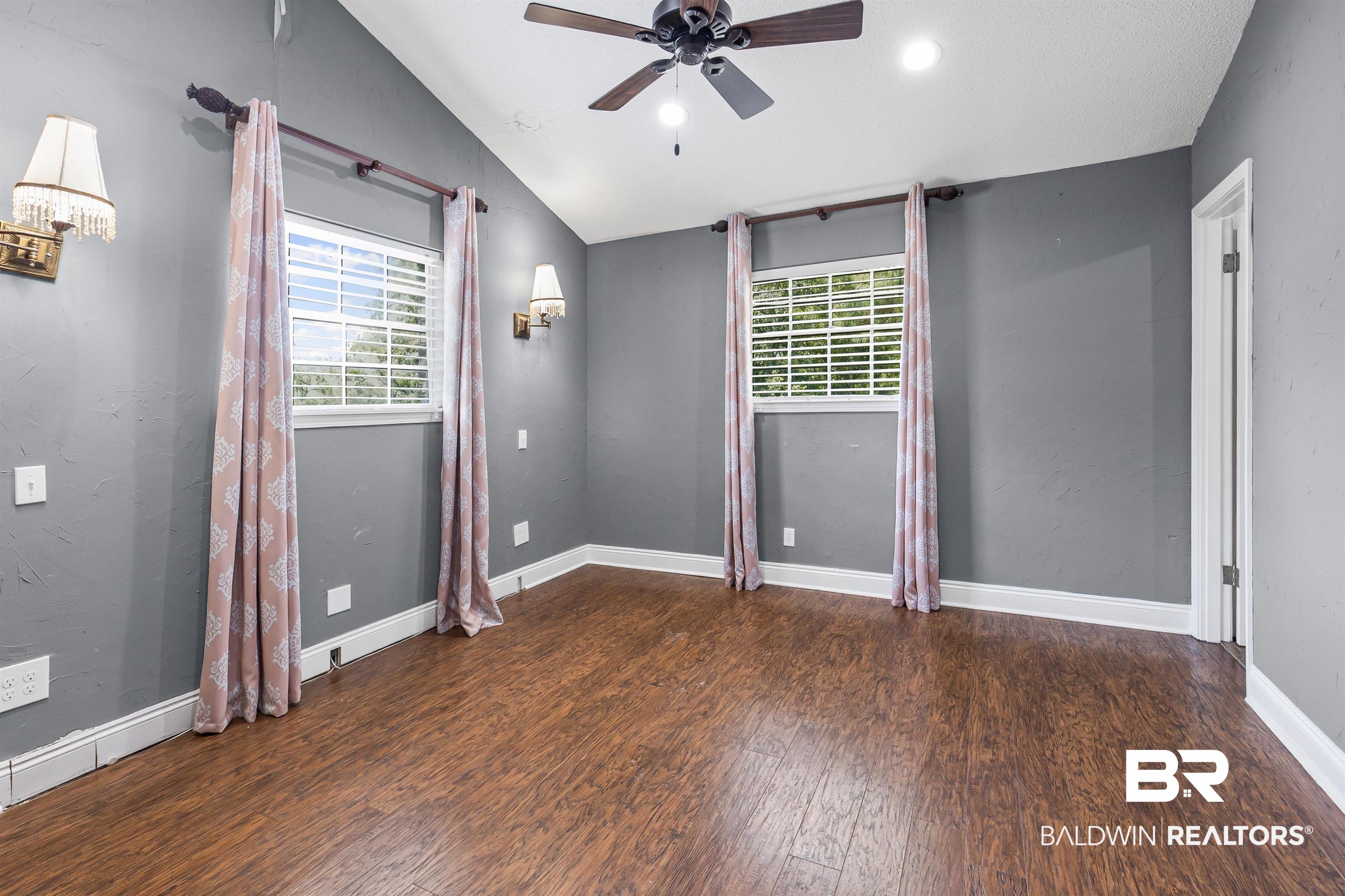 36 Ridgeview Drive Mobile, AL 36611 - Photo 8 of 20 Unfurnished primary bedroom featuring vaulted ceiling, a ceiling fan, multiple windows, dark wood-type flooring, and recessed lighting