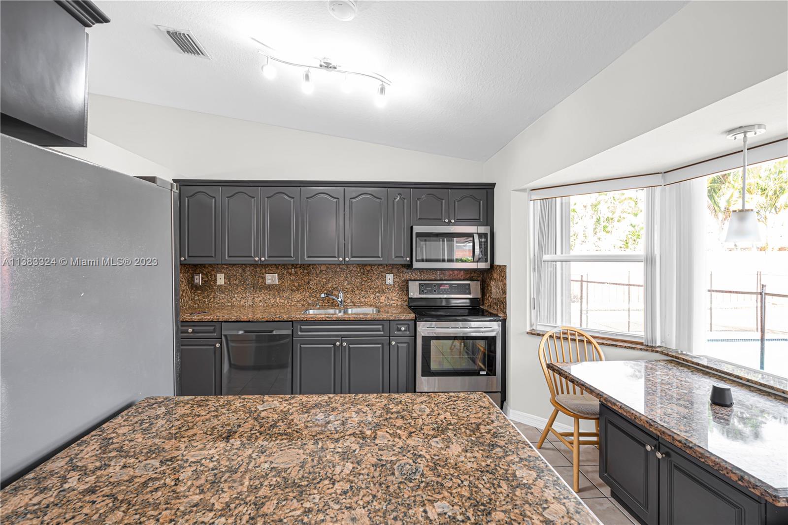 14809 Southwest 180th Street Miami, FL 33187 - Photo 12 of 38 a kitchen with stainless steel appliances granite countertop a sink stove and refrigerator
