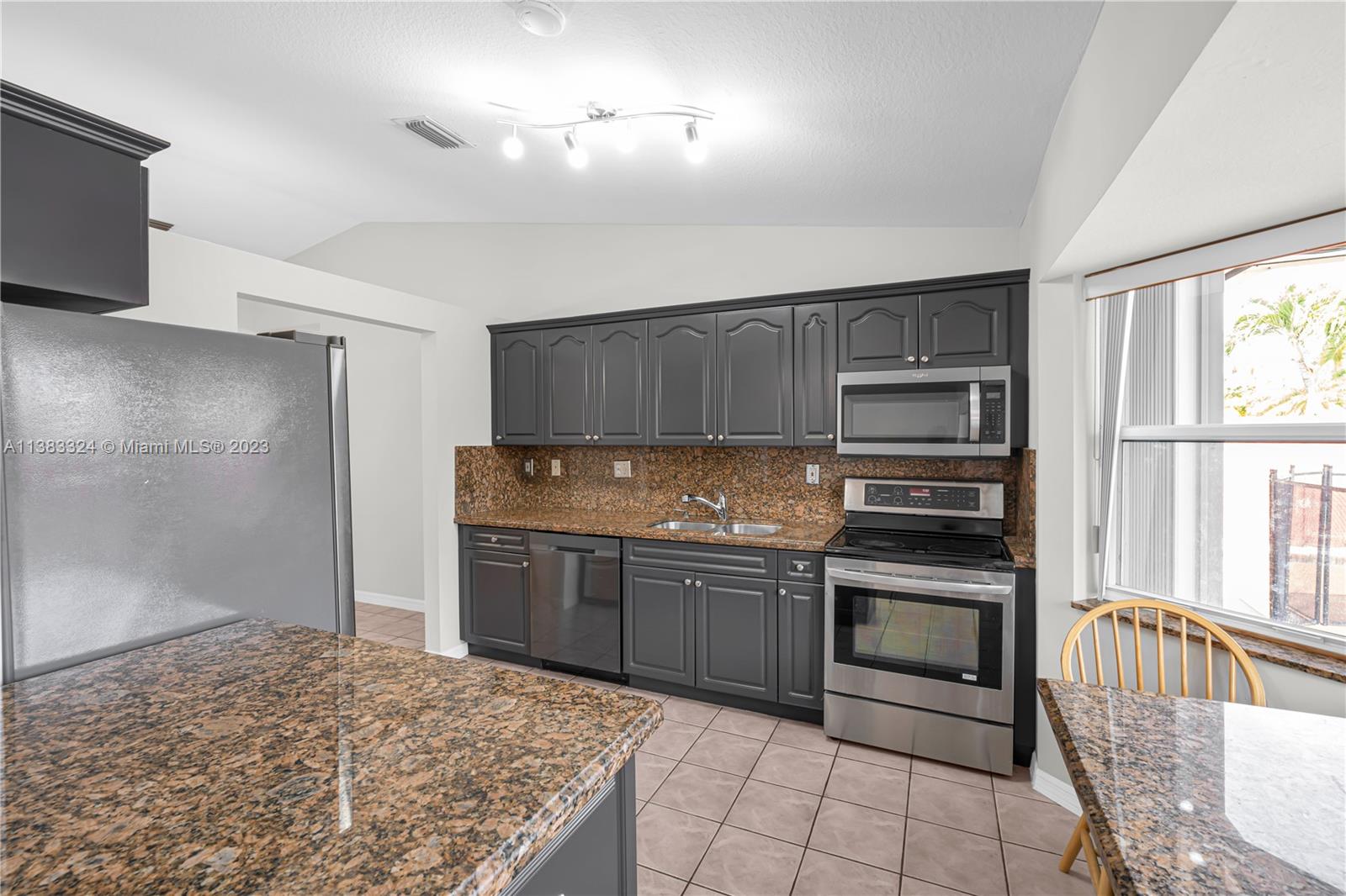 14809 Southwest 180th Street Miami, FL 33187 - Photo 13 of 38 a kitchen with stainless steel appliances granite countertop a stove and a refrigerator