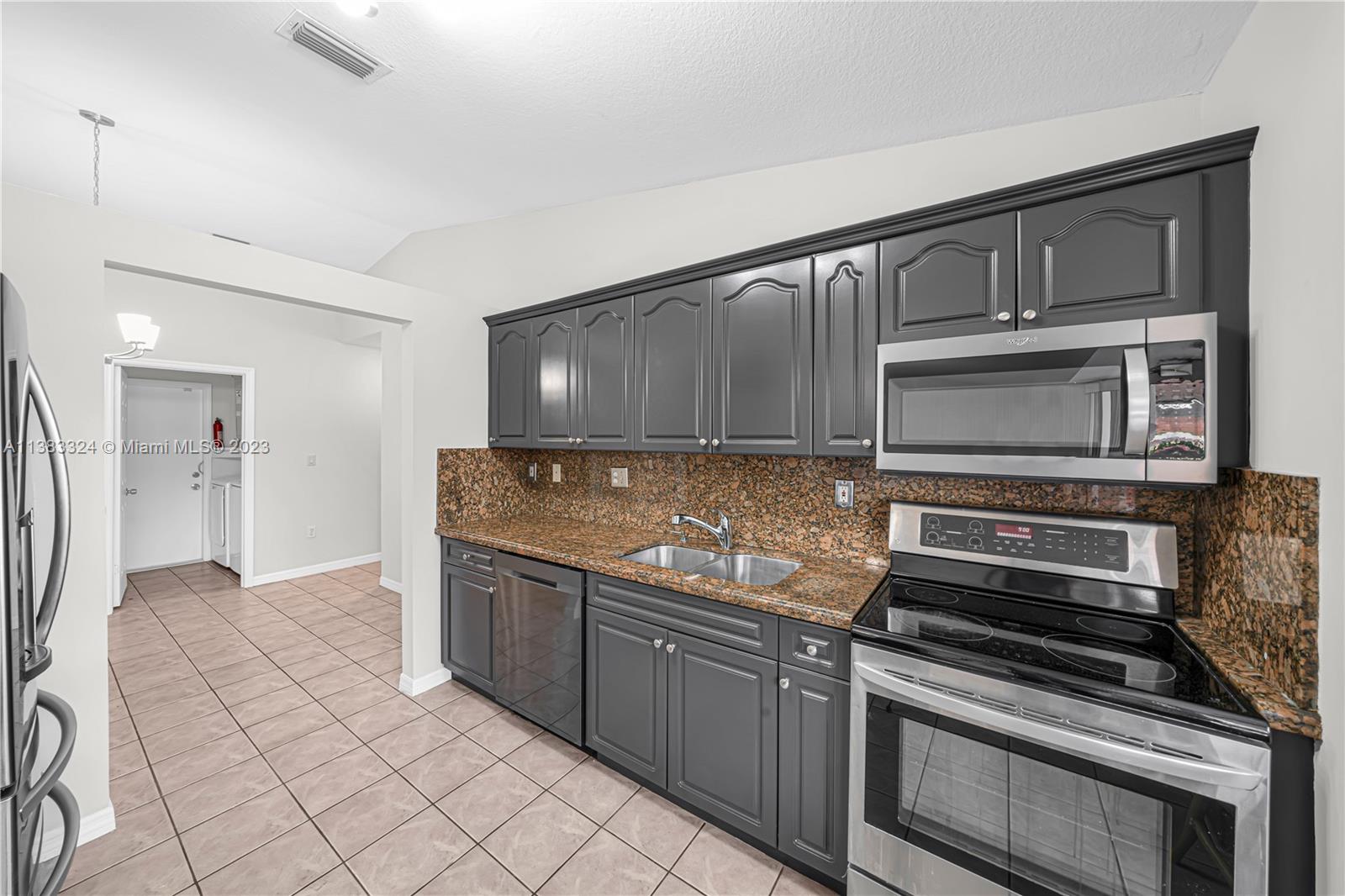 14809 Southwest 180th Street Miami, FL 33187 - Photo 15 of 38 a kitchen with granite countertop a stove and a microwave