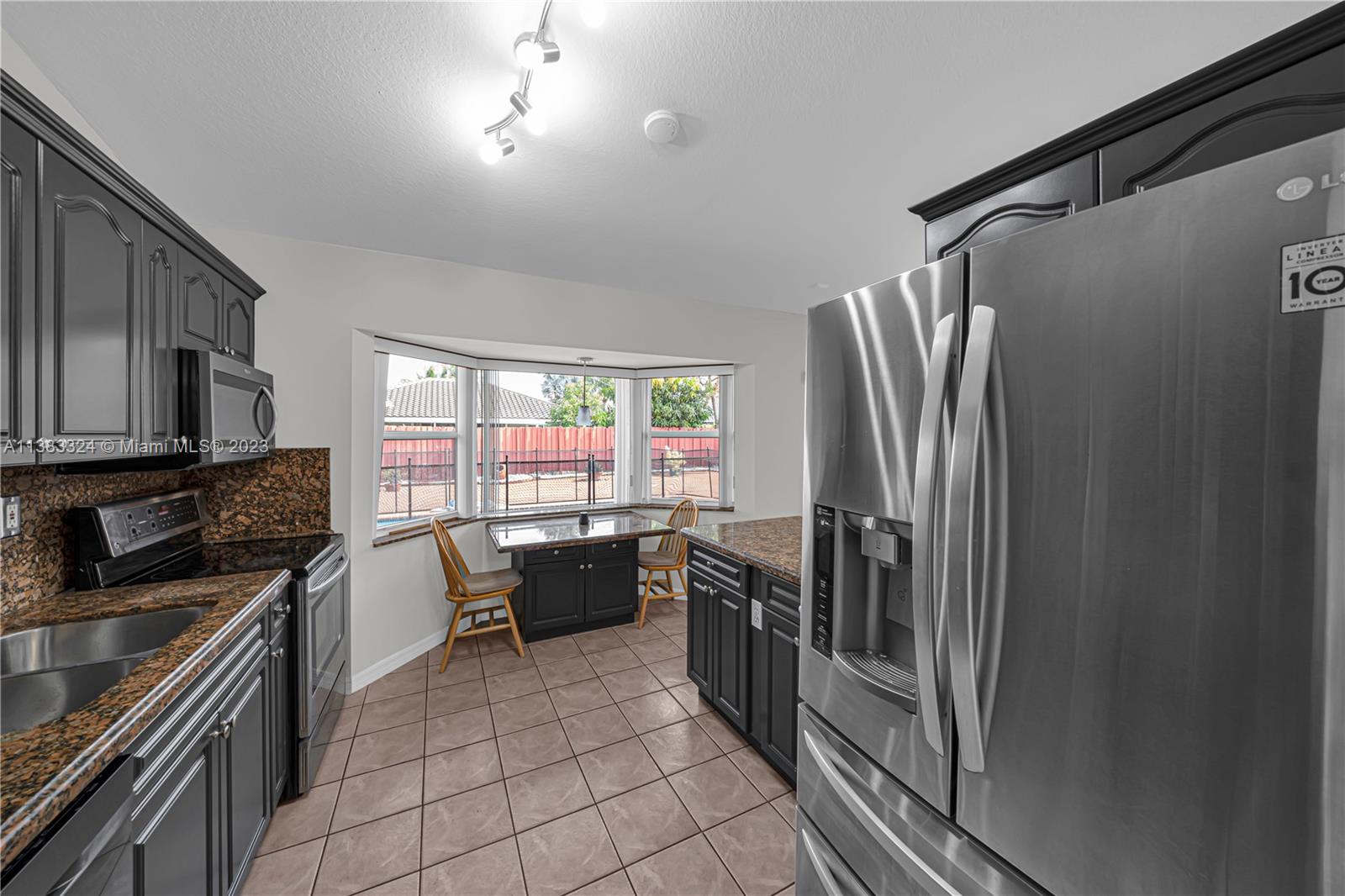 14809 Southwest 180th Street Miami, FL 33187 - Photo 16 of 38 a kitchen with stainless steel appliances granite countertop a refrigerator stove and sink