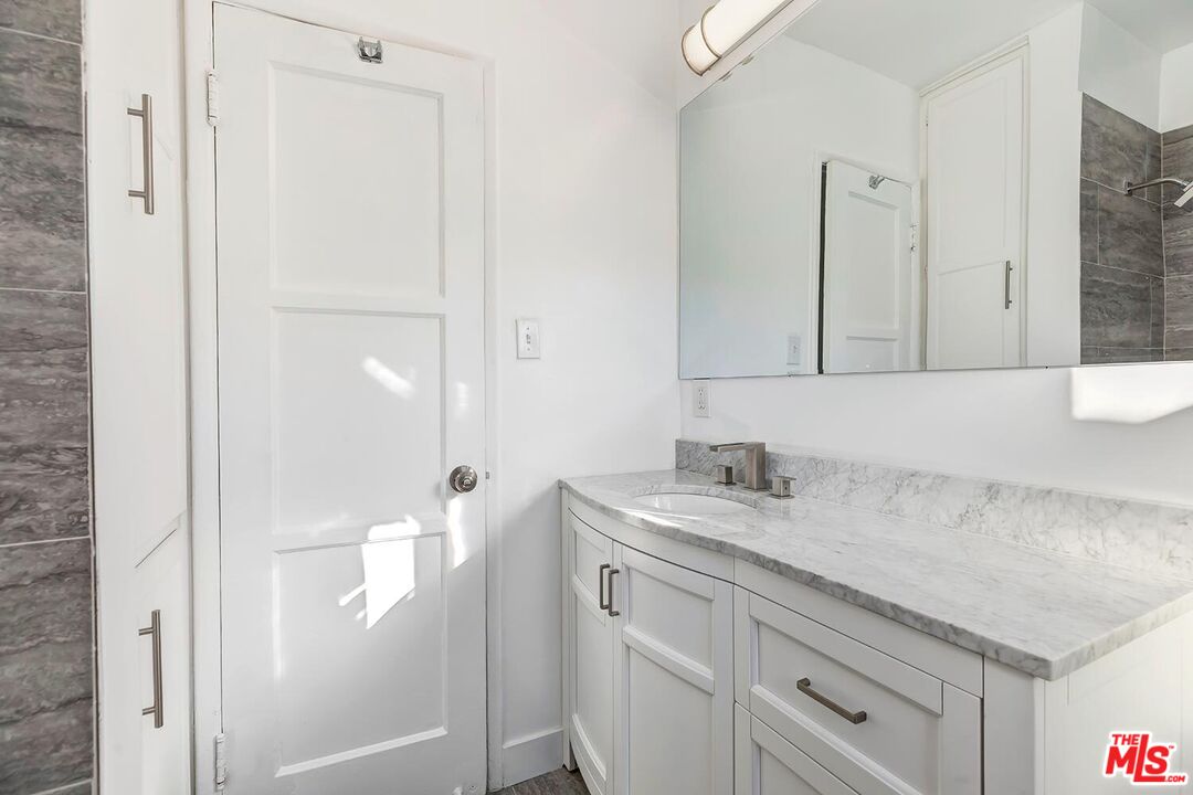 5022 Clinton Street, Unit 5022B Los Angeles, CA 90004 - Photo 17 of 22 a bathroom with a granite countertop sink and a mirror