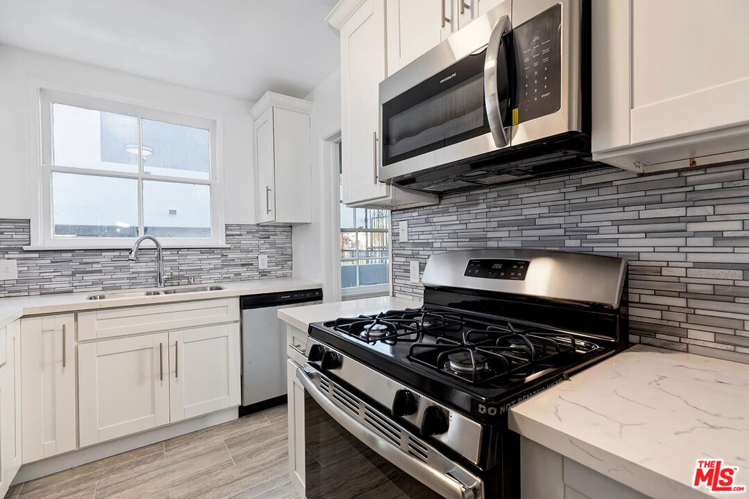 5022 Clinton Street, Unit 5022B Los Angeles, CA 90004 - Photo 9 of 22 a kitchen with stainless steel appliances a stove a sink and wooden cabinets