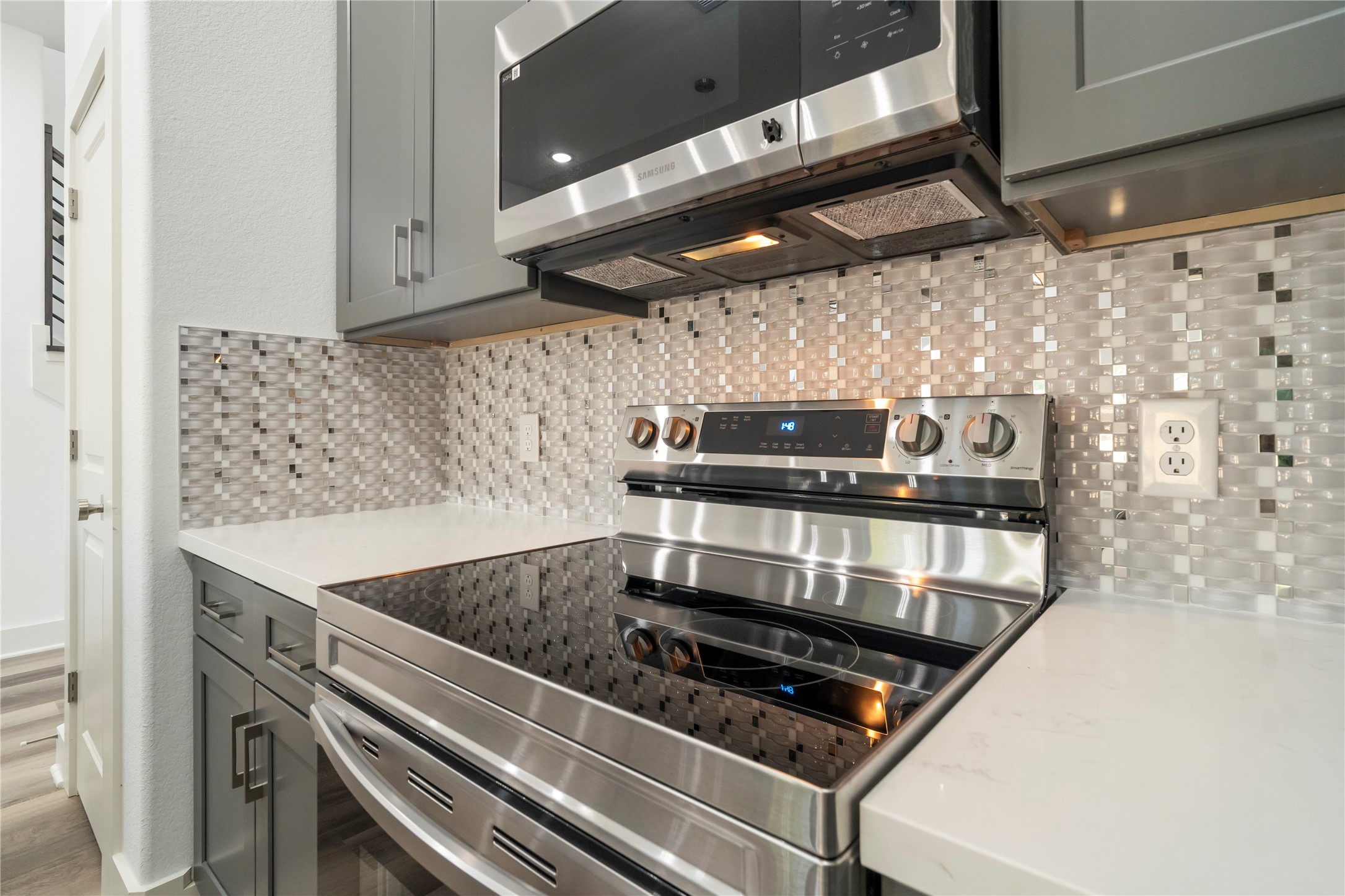 5629 Malmedy Road Houston, TX 77033 - Photo 5 of 24 Modern kitchen with sleek stainless steel appliances, elegant gray cabinetry, and a stylish mosaic tile backsplash.