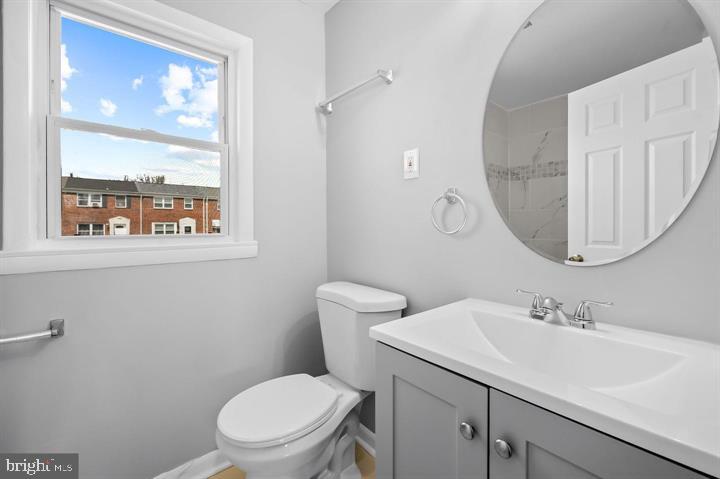 631 Charraway Road Baltimore, MD 21229 - Photo 17 of 25 a bathroom with a toilet a sink a mirror and a window