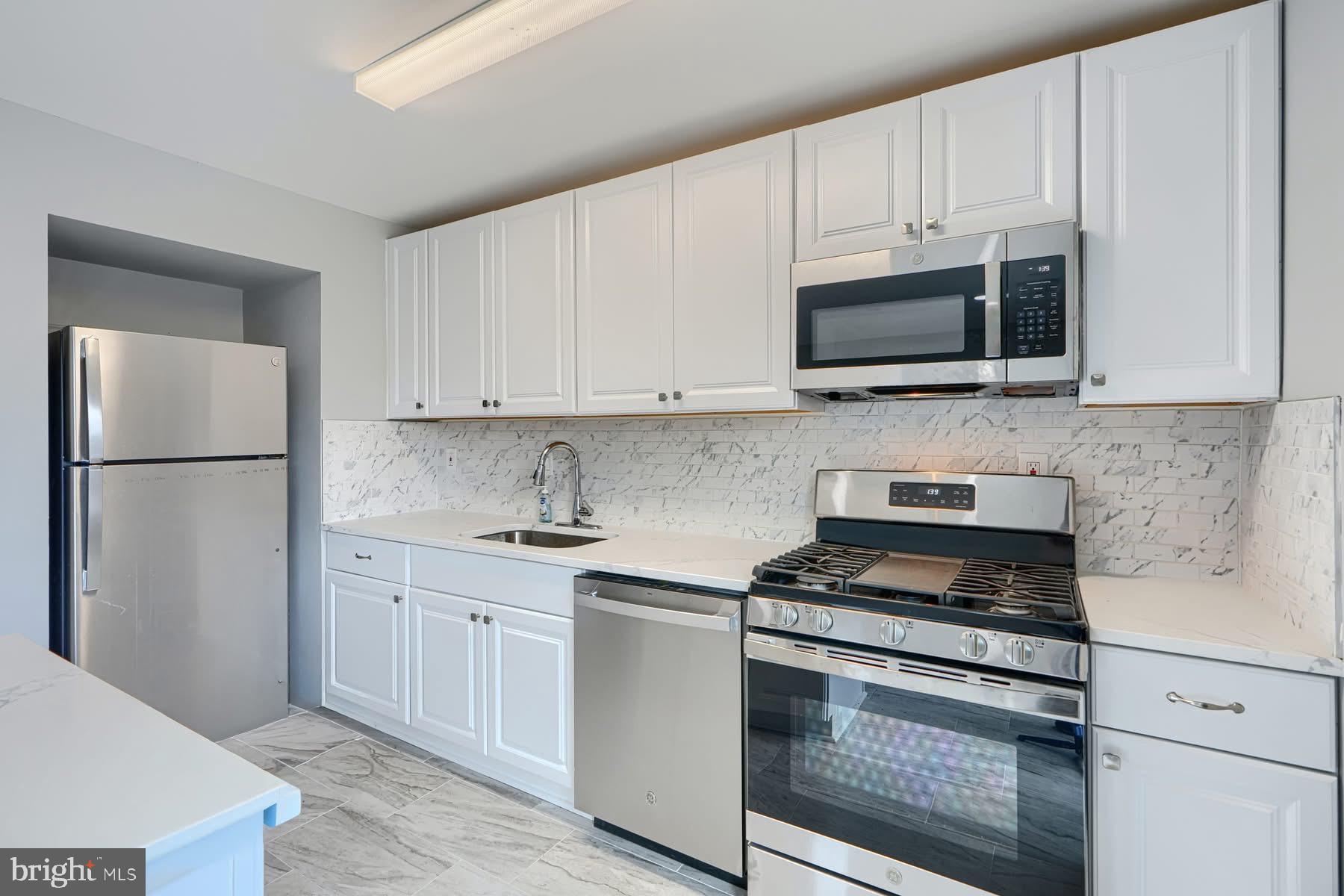 631 Charraway Road Baltimore, MD 21229 - Photo 6 of 25 a kitchen with stainless steel appliances granite countertop white cabinets stove a refrigerator and a microwave