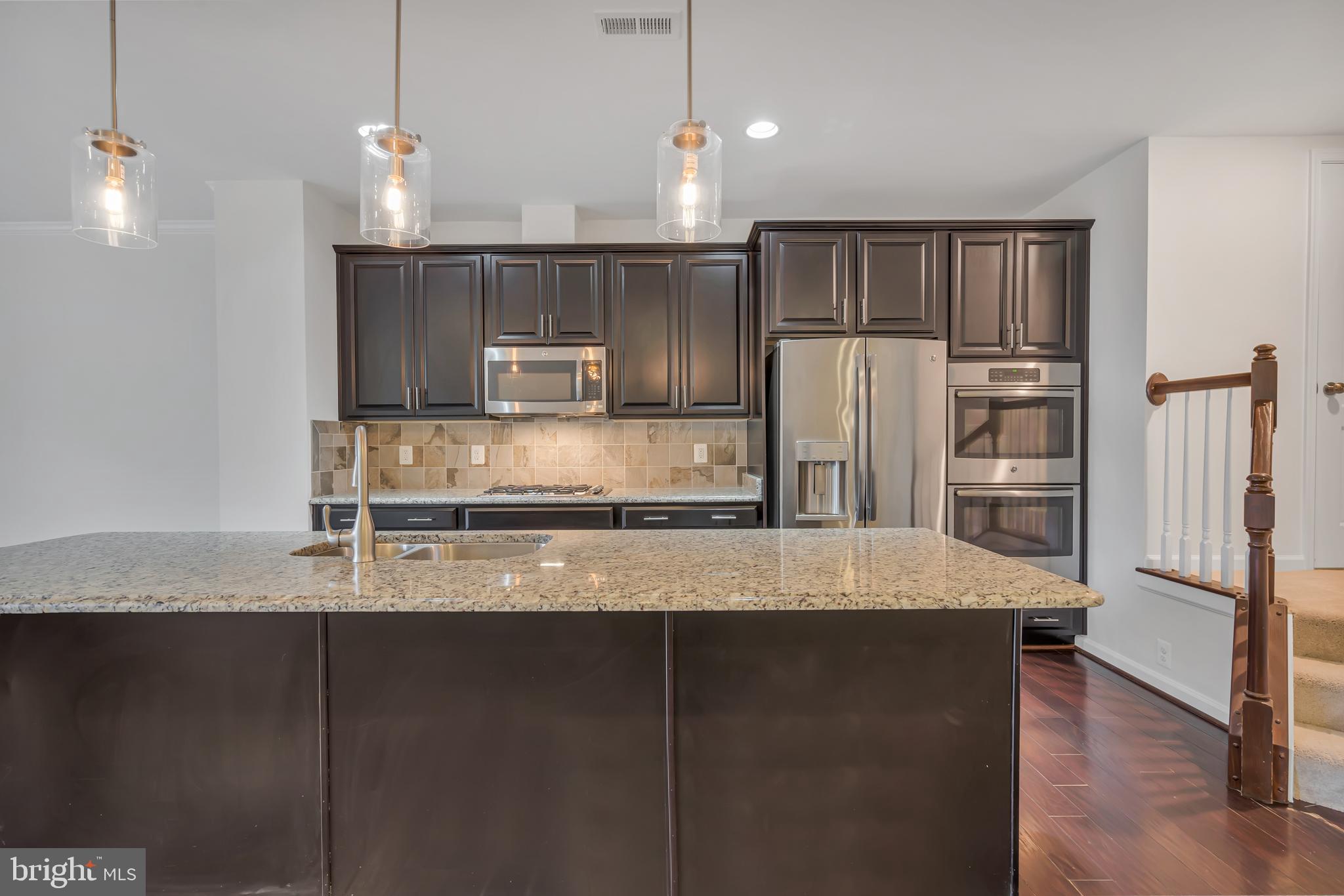 42482 Benfold Square Ashburn, VA 20148 - Photo 3 of 34 a kitchen with kitchen island granite countertop a refrigerator a sink and a stove