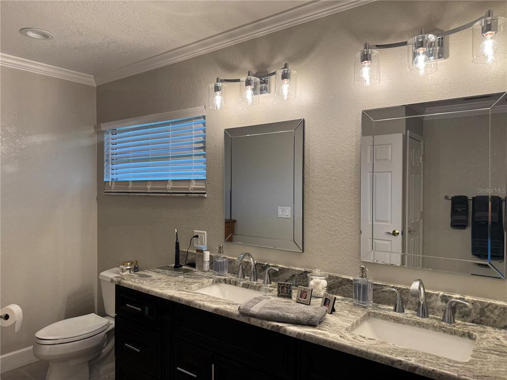 334 West F Street Frostproof, FL 33843 - Photo 29 of 48 a bathroom with a granite countertop sink a toilet a large mirror and shower