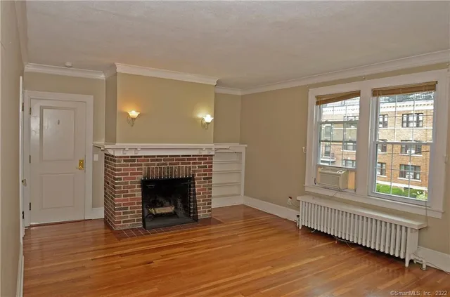 an empty room with wooden floor fireplace and windows