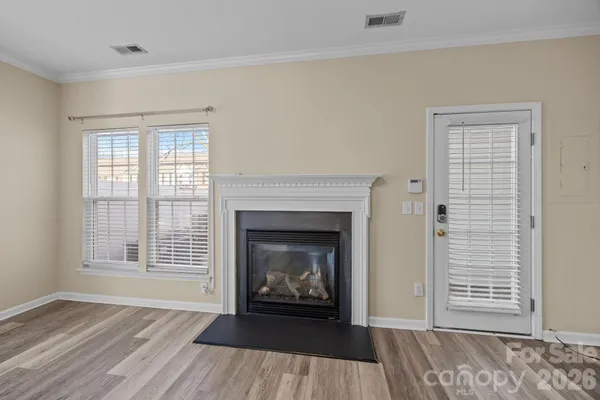 a view of an empty room with wooden floor fireplace and a window