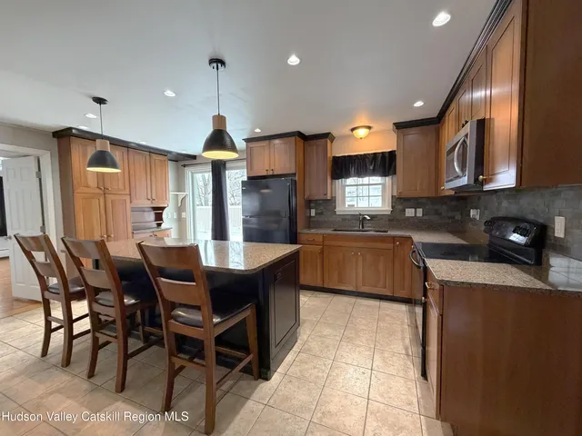 a kitchen with stainless steel appliances granite countertop wooden cabinets a center island a stove and a wooden cabinets