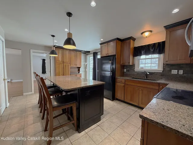 a kitchen with granite countertop kitchen island stainless steel appliances a sink stove and refrigerator