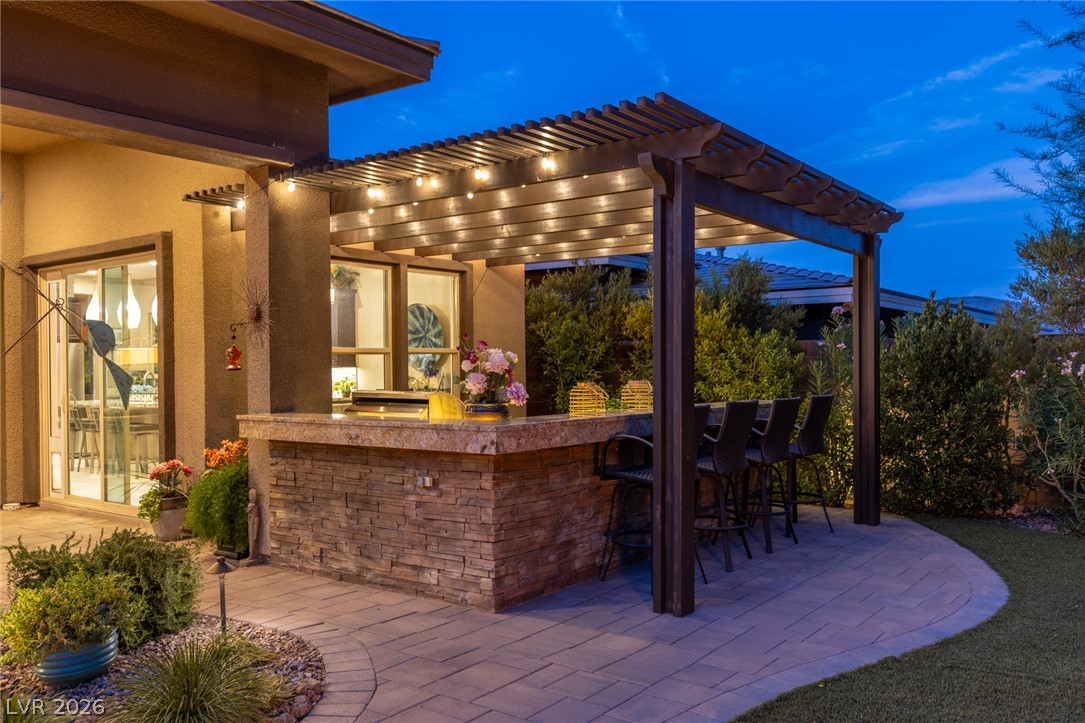 10167 Copper Edge Road Las Vegas, NV 89148 - Photo 39 of 45 An inviting outdoor kitchen area with a stone bar and pergola offers exceptional evening entertainment.