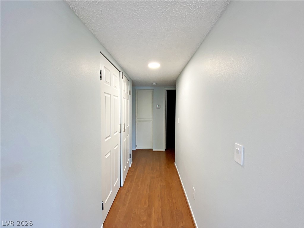 1575 West Warm Springs Road, Unit 1024 Henderson, NV 89014 - Photo 12 of 25 A well-lit hallway presents hardwood-style flooring leading to a discreet entry.