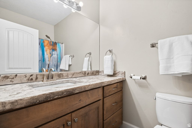 175 West 1000 North Mapleton, UT 84664 - Photo 23 of 42 Bathroom featuring a wood-finish vanity with a built-in sink, stone countertop, brushed nickel fixtures, and a toilet