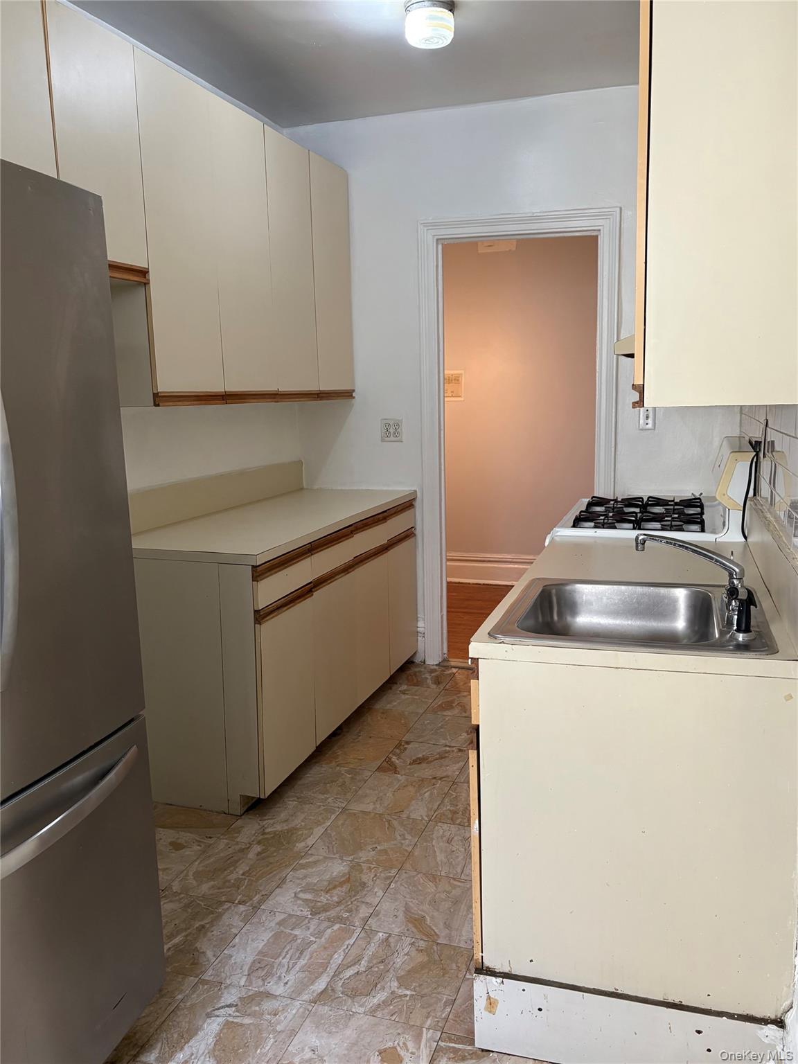 5005 43rd Avenue, Unit 5H Queens, NY 11377 - Photo 12 of 23 Kitchen featuring freestanding refrigerator, range with gas stovetop, light countertops, light stone finish flooring, and backsplash