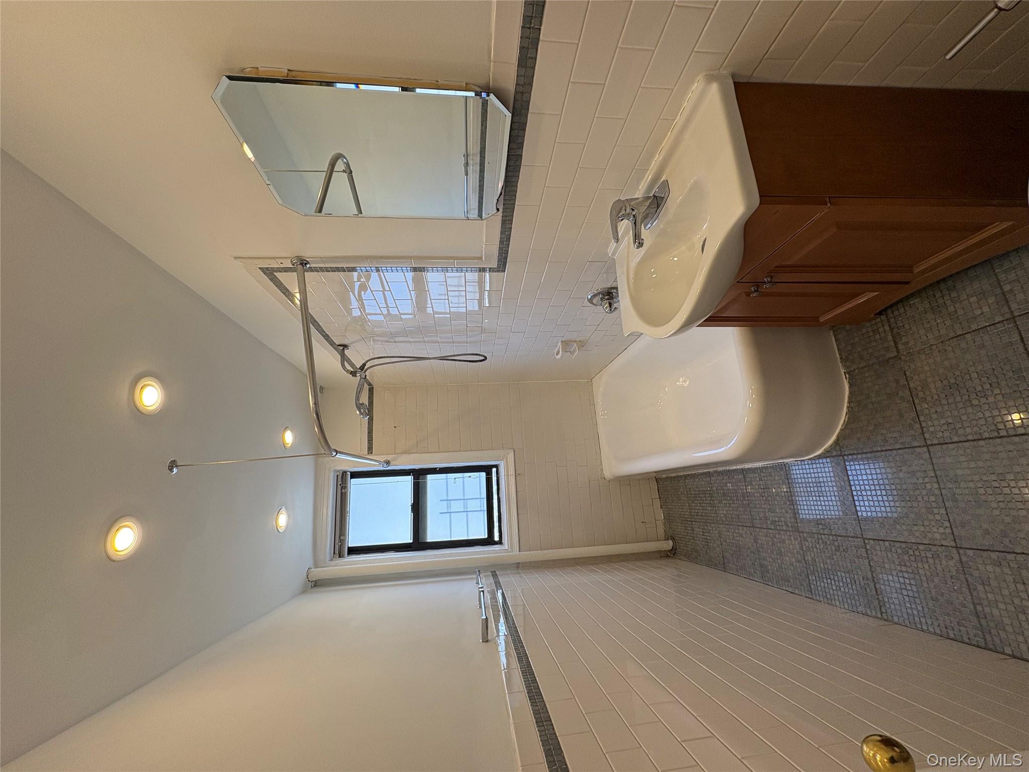5005 43rd Avenue, Unit 5H Queens, NY 11377 - Photo 19 of 23 Bathroom with tile walls, tub / shower combination, vanity, wainscoting, and dark tile patterned floors