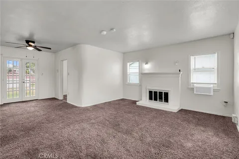 an empty room with windows and fireplace