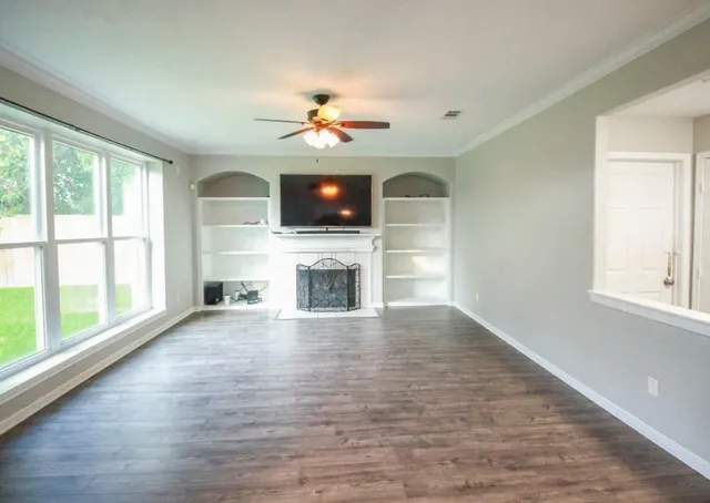 a view of a livingroom with a fireplace a ceiling fan and windows